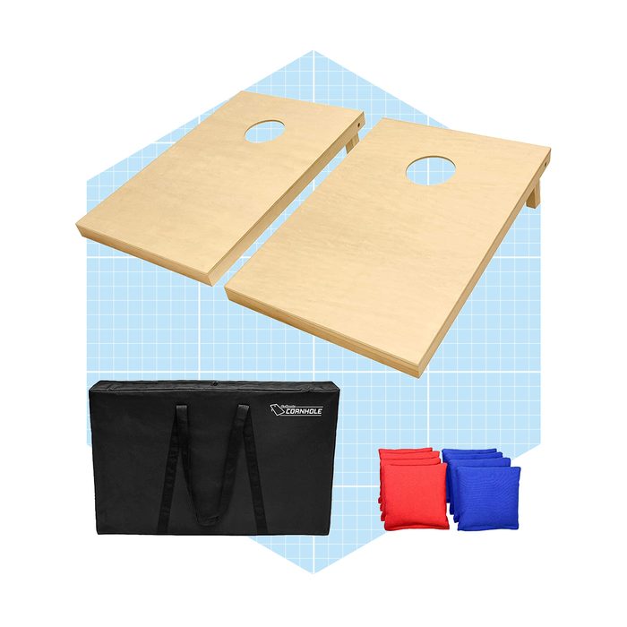 Two cornhole boards with holes rest above a black carrying case, accompanied by red and blue bean bags on a blue grid background.