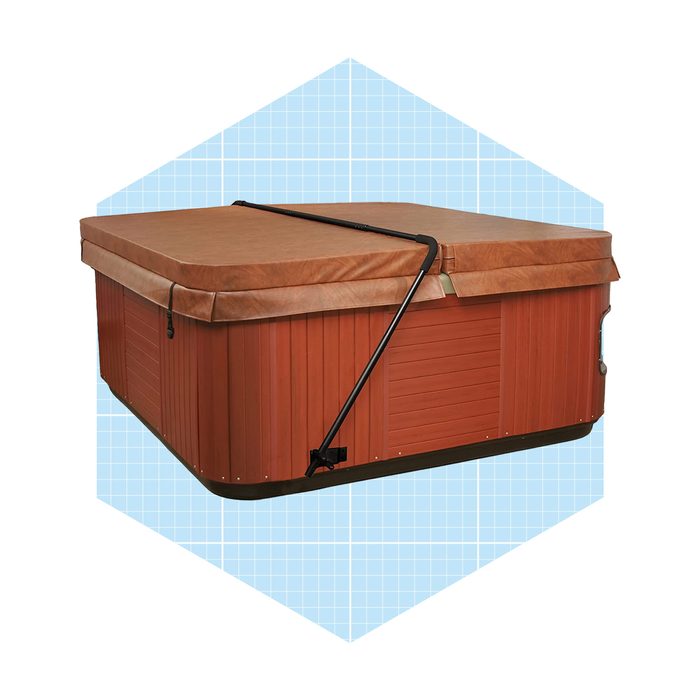 A wooden hot tub with a brown cover is secured with a strap on a light blue grid background, suggesting a clean, modern setting.