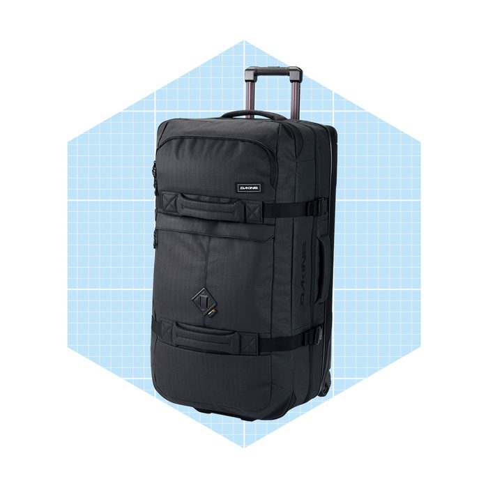 A large, black wheeled backpack stands upright, featuring zippers and straps against a light blue geometric background, suggesting travel or adventure readiness.
