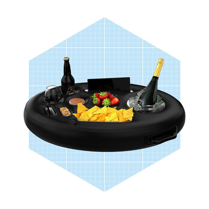 A black serving tray holds nachos, strawberries, a beer bottle, and champagne in ice, set against a light blue grid background.
