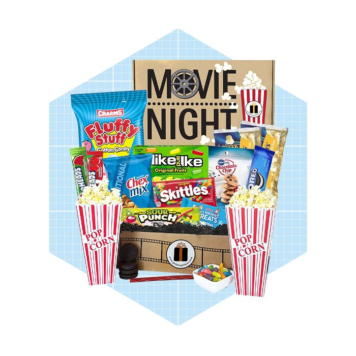 A variety of snacks, including popcorn, candy, and cookies, are arranged alongside a 