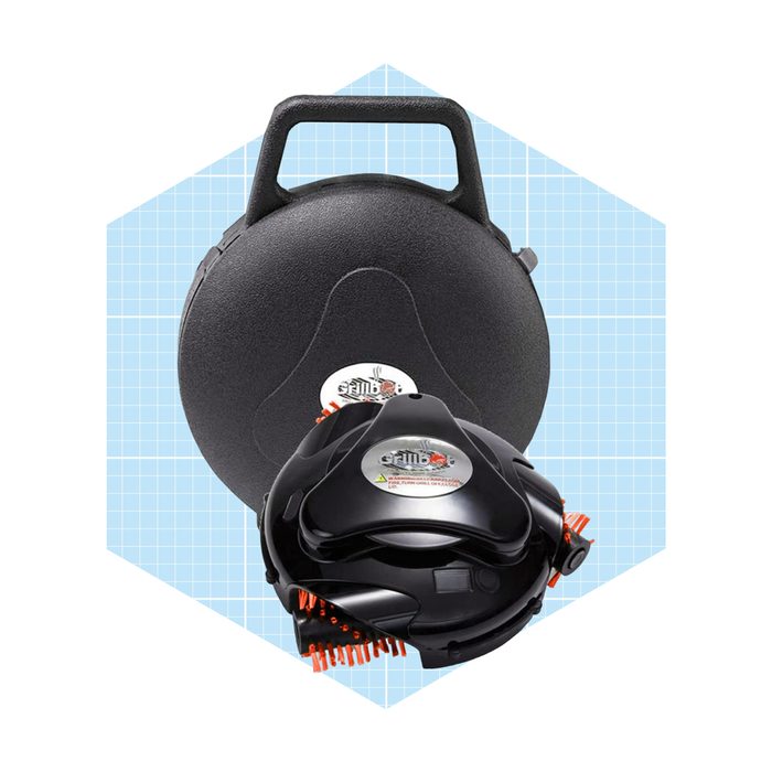 A black cleaning tool with orange bristles is positioned in front of a circular carrying case, set against a light blue grid background.