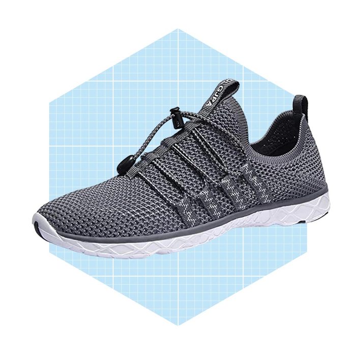 A grey athletic shoe is displayed, designed with a mesh upper and elastic laces, set against a light blue hexagonal background with grid patterns.