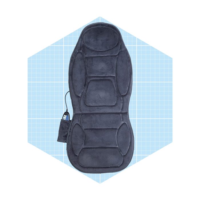 A gray massage mat lies flat with a power cord attached, set against a light blue grid background, designed for relaxation and comfort.