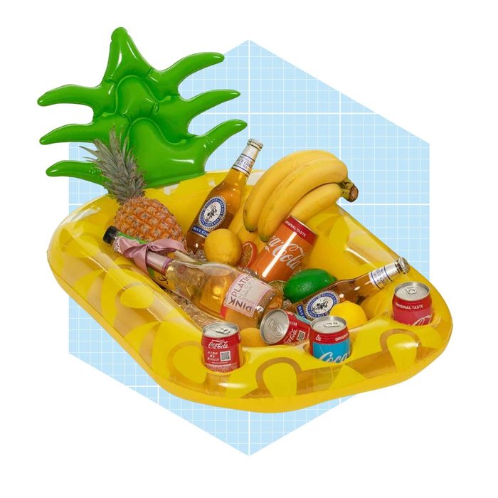 A yellow inflatable tray filled with drinks and fruits, including bananas and a pineapple, has a green palm design, set against a light blue grid background.