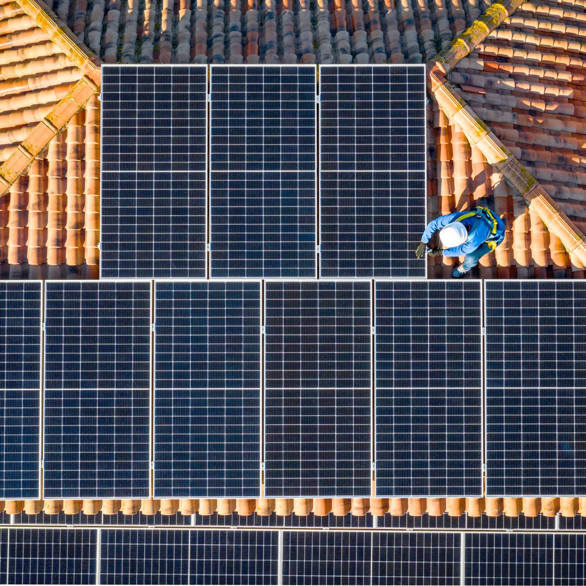 aerial view of Two workers installing solar panels on a house roof