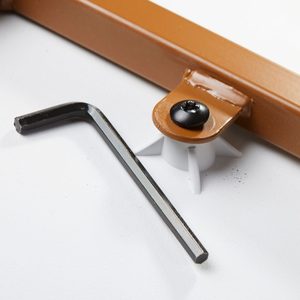 A black hex key lies next to a brown plastic mount secured by a black screw, placed on a light surface.
