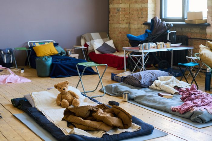Part of spacious room with sleeping places on wooden floor for refugees