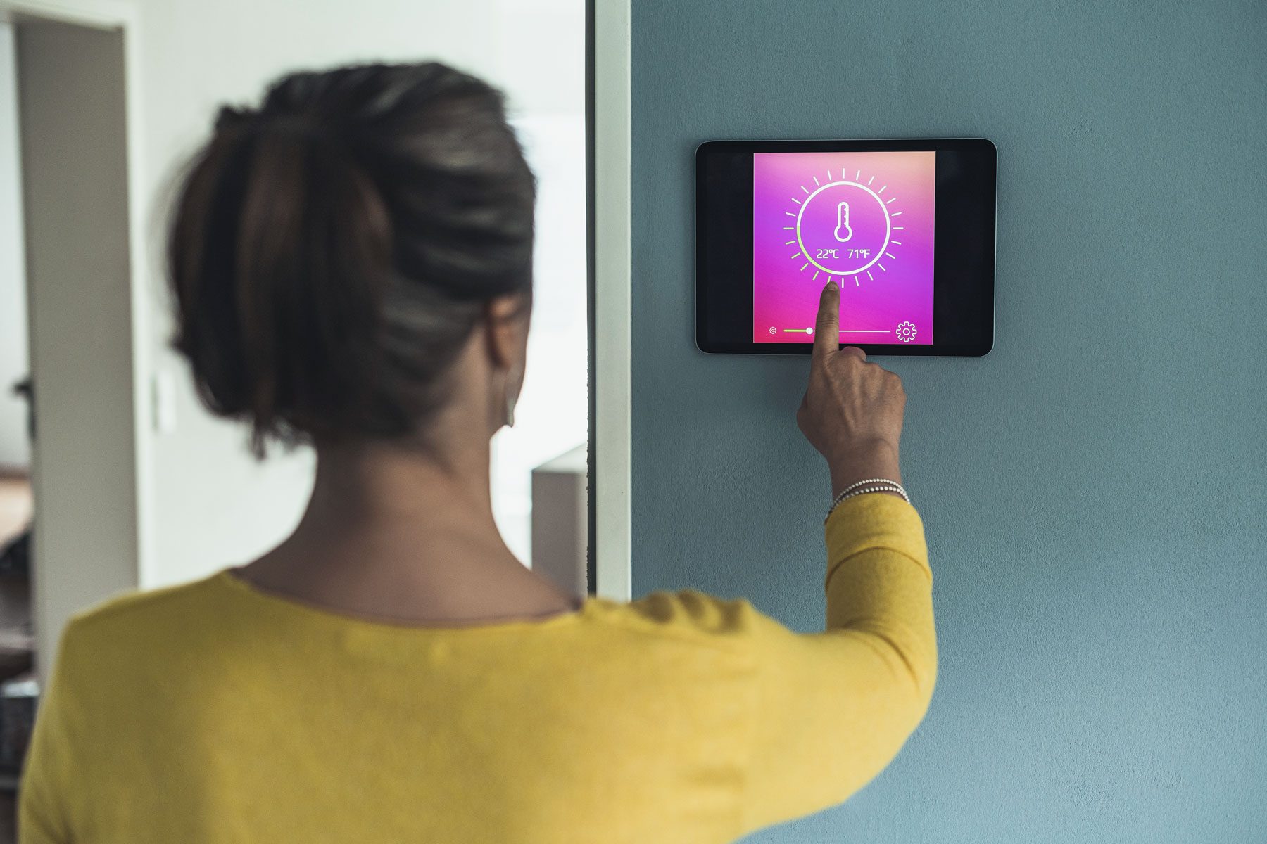 A woman setting temperature in thermostat