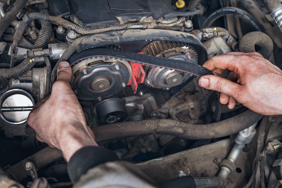 mechanic changing timing belt in car