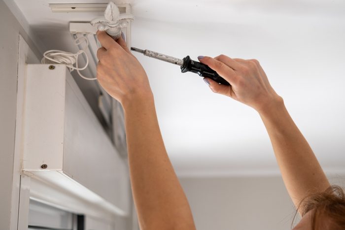 Handywoman replacing roller blind cord using screwdriver at home