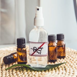 Homemade essential oil based mosquito repellent. Flat lay view of spray bottle surrounded by brown essential oil bottles on bamboo mat background.
