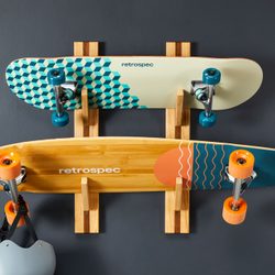 Two skateboards hanging on a wall rack; the skateboards are both facing upwards, the helmet is hanging on a hook
