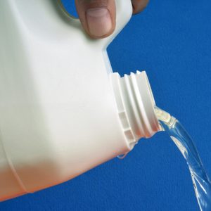Carton of bleach pouring out in front of a blue background