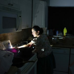 Woman uses phone flashlight to illuminate her kitchen during a power blackout