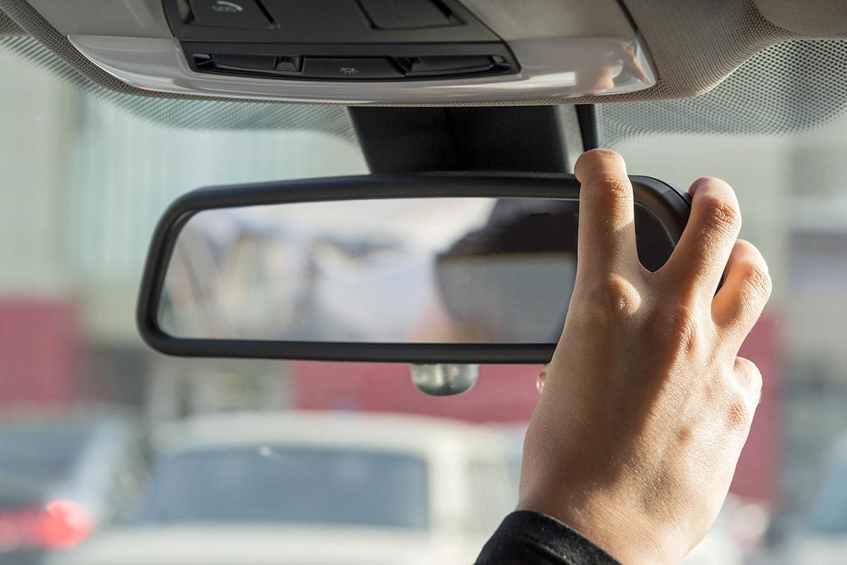 girl adjusts the rearview mirror in a car