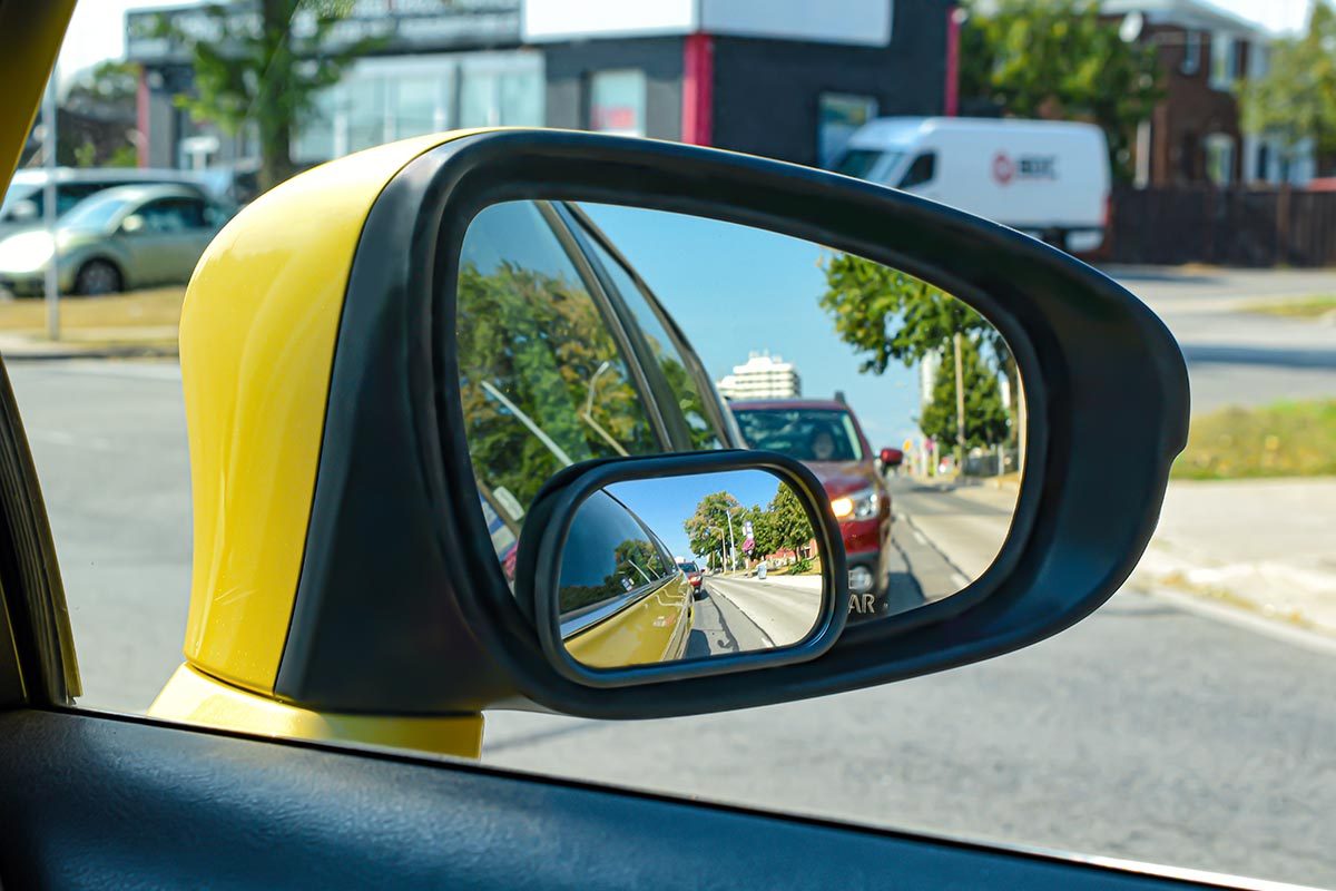 The view from a motor vehicle side mirror through the window.